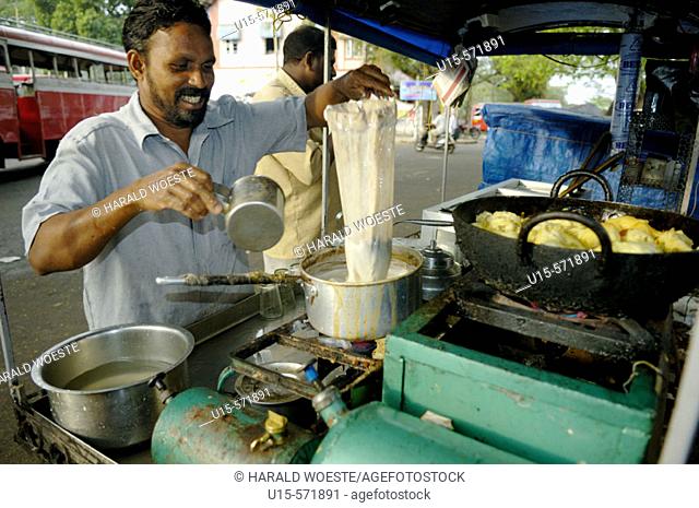 Indian street cook preparing tea and streetfood (pakora, fritters) in his small mobile cook-shop. Fort Cochin (Kochi), Kerala, India 2005