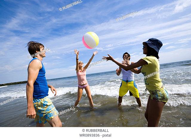 Four young people playing with a beach ball
