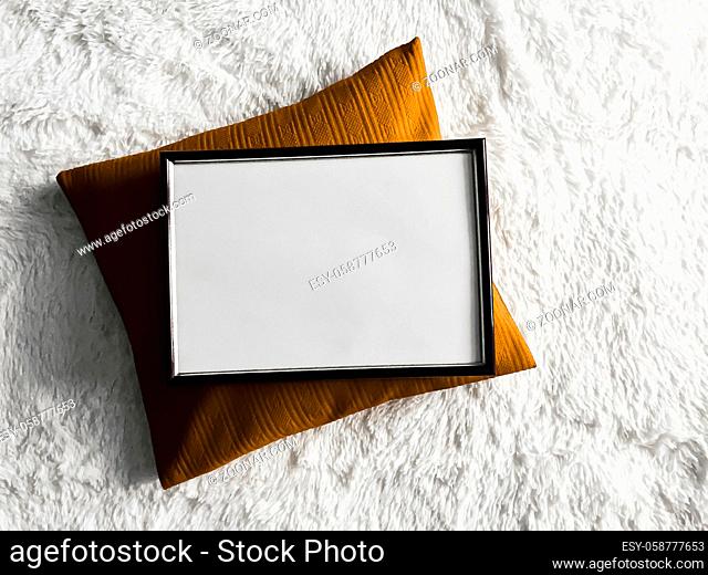 Black thin wooden frame with blank copyspace as poster photo print mockup, golden cushion pillow and fluffy white blanket, flat lay background and art product