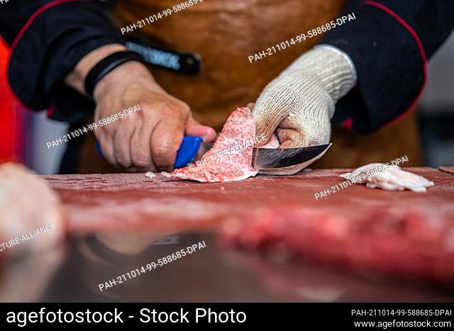 PRODUCTION - 16 June 2021, North Rhine-Westphalia, Münster: In a butcher shop, a butcher cuts up a previously slaughtered Wagyu steer
