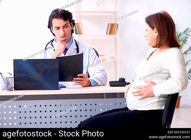 Old pregnant woman visiting young male doctor