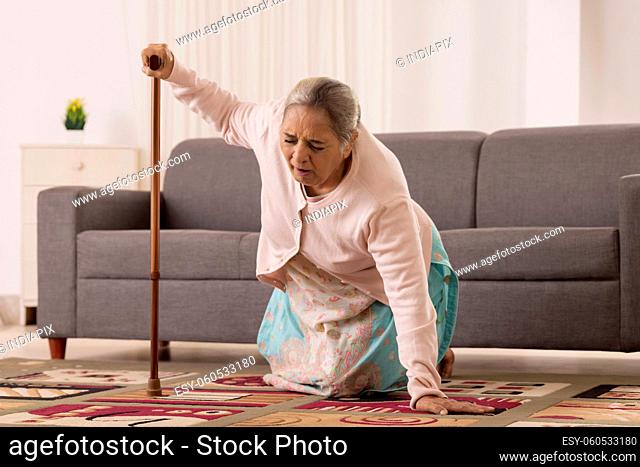Old woman trying to stand with the help of walking stick