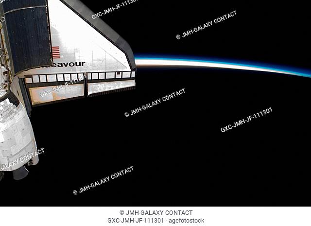 Intersecting the thin line of Earth's atmosphere, space shuttle Endeavour's starboard wing is featured in this image photographed by an Expedition 22 crew...