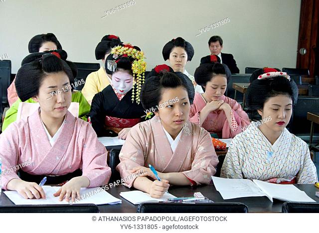 Geisha and Maiko apprentice Geisha attending a class at 'Mia Garatso' school of Geisha while there are three young women wearing plain kimono seated at desk in...