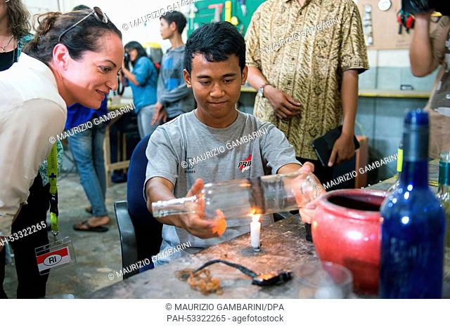 German actress Natalia Woerner (L) looks on as a boy shapes a glass bottle at a apprentice workshop in Jakarta, Indonesia, 3 November 2014