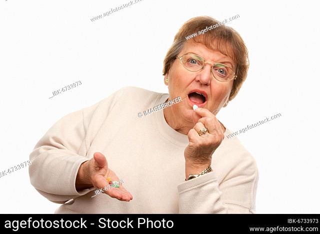 Attractive senior woman taking pills isolated on a white background
