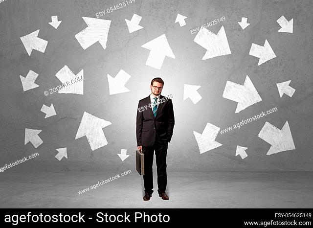 Handsome businessman standing in front of a wall with chalk drawn arrows