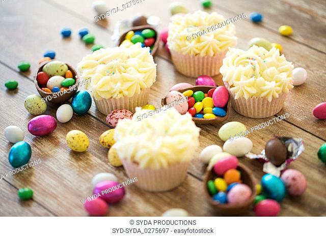 cupcakes with easter eggs and candies on table
