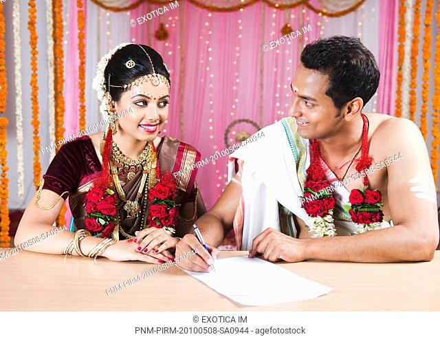 Newlywed couple signing a marriage certificate