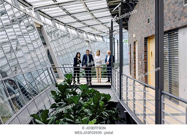 Business people standing on skywalk in modern office building