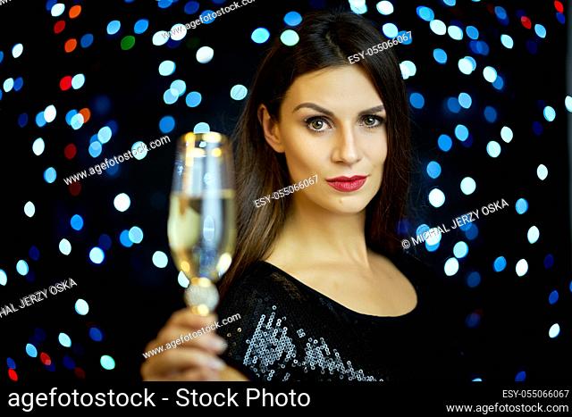 beautiful young smiling woman with one glass of champagne on a black background in New Year's Eve
