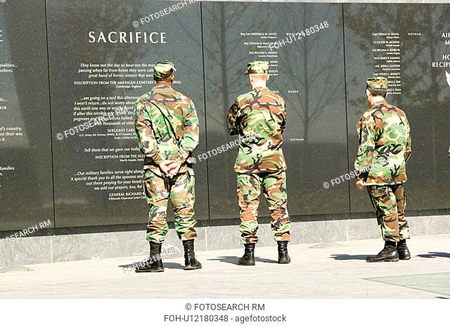 Three servicemen look at granite inscription on wall of Air Force Memorial, Arlington, Virginia in Washington D.C. area