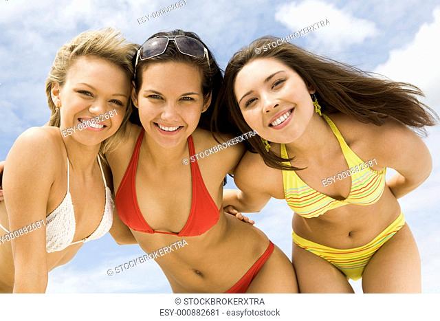 Portrait of happy girls in bikini embracing each other and looking at camera