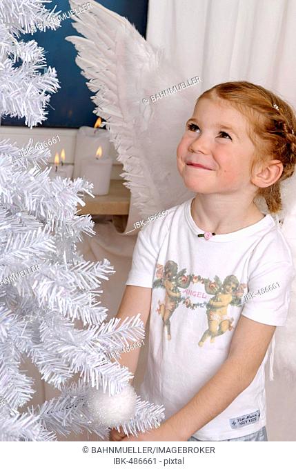 Child decorates a white christmas tree