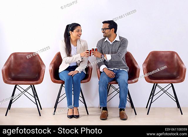 Office colleagues in rest room with coffee cups during leisure period