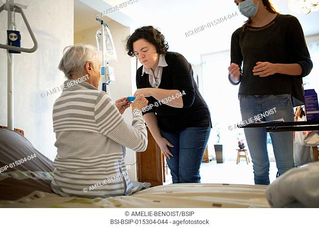 Reportage on a home health care service in Savoie, France. An auxiliary nurse gives a patient a tablet container box