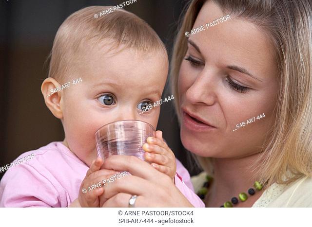 Mother giving her daughter glass of water, Engen, Baden-Wuerttemberg, Germany