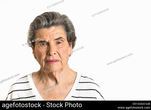 Portrait of elderly lady in casual shirt looking seriously at camera isolated on white background