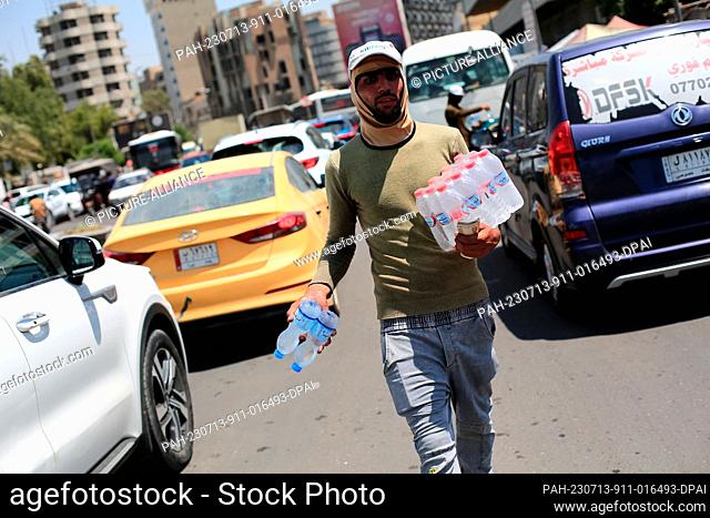 13 July 2023, Iraq, Baghdad: A vendor sells cold water to drivers during a hot summer day at Al-Shorja market. Photo: Ameer Al-Mohammedawi/dpa