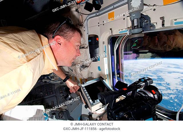 NASA astronaut Terry Virts, STS-130 pilot, looks through an overhead window on the aft flight deck of space shuttle Endeavour during flight day 13 activities