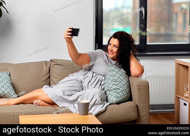 happy woman taking selfie with smartphone at home