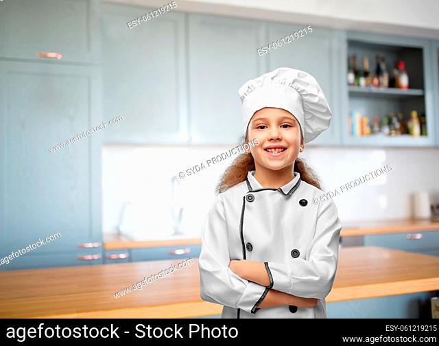 smiling little girl in chef's toque in kitchen