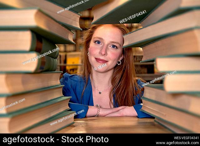 Beautiful woman with long hair seen through stack of books