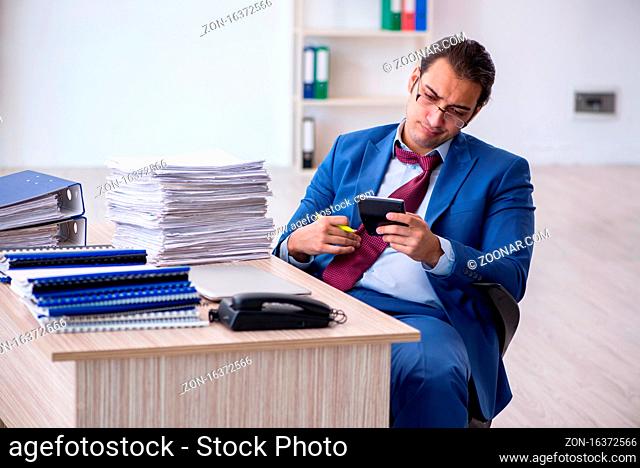 Young male bookkeeper calculating expences in the office