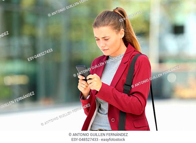 Worried young businesswoman using a mobile phone on the street