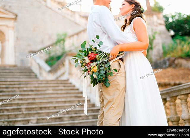 Bride and groom embracing on the ancient bell tower near the church in Prcanj, bride holding wedding bouquet in her hand . High quality photo