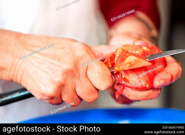 Woman cutting a tomato with a knife. Preparation of products for cooking