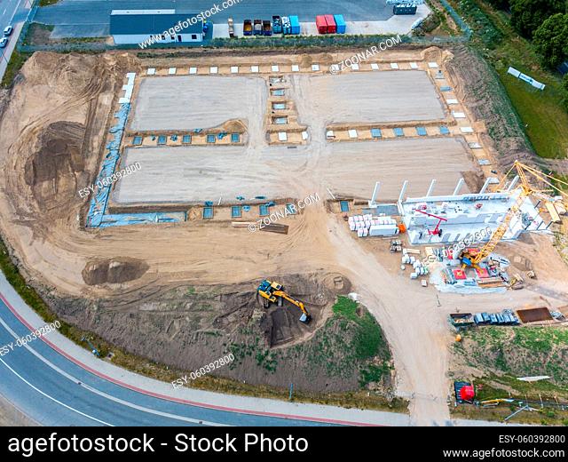 Drone photos of a large construction site on which a factory building is being erected. The foundations for the piers have been laid and and the first piers...