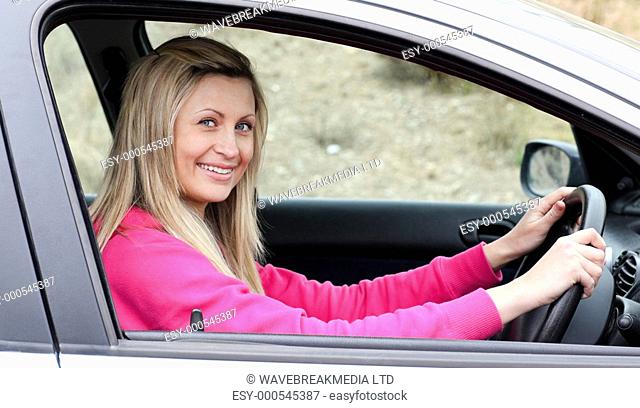 Smiling female driver at the wheel in her new car