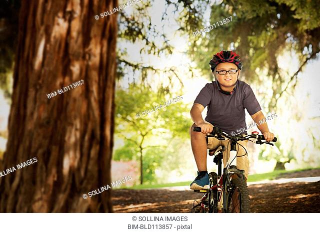 Mixed race boy riding mountain bike in forest