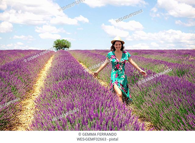 France, Provence, Valensole plateau, smiling woman walking among lavender fields in summer