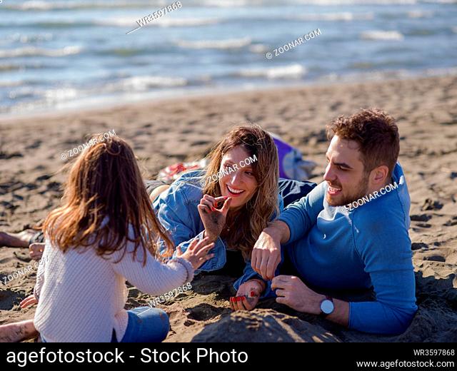 Family with little daughter resting and having fun at beach during autumn day