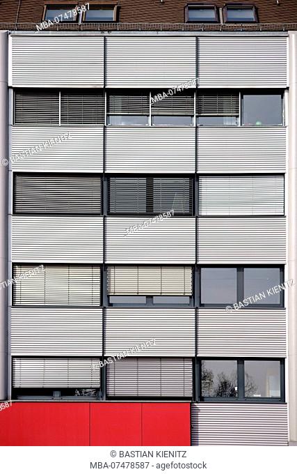 Modern facade of an office building with rows of windows and metal blinds