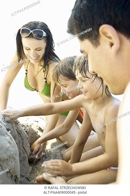 Family playing in sand on beach together