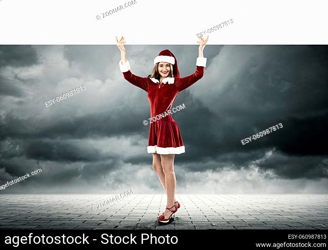 Full length of Christmas Santa girl holding white blank banner above head