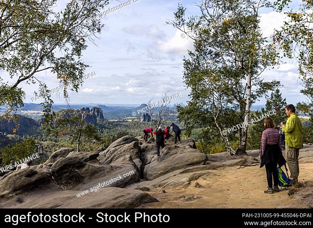 05 October 2023, Saxony, Schmilka: Hikers have climbed to a vantage point in the ""Saxon Switzerland"" National Park and are enjoying the view over the rocky...