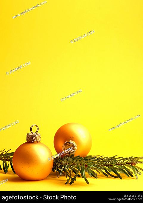 Two golden vintage Christmas baubles on a yellow background with space for your text or image, seasonal holiday concept