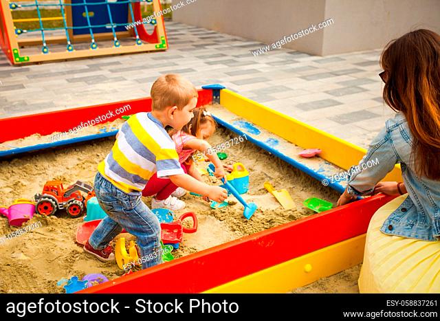 Happy toddler boy and girl playing in sand on outdoor playground. Happy and healthy childhood