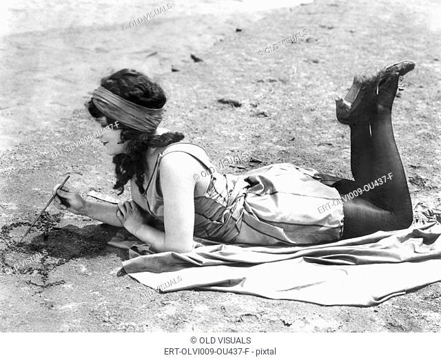 Young woman drawing a heart in the sand