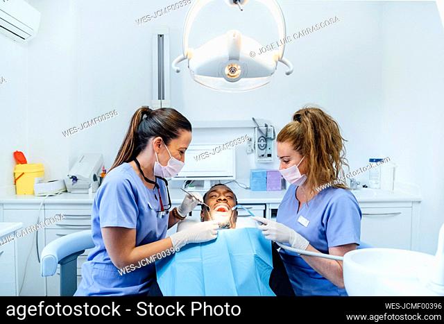 Female dentist and assistent attending patient in medical practice