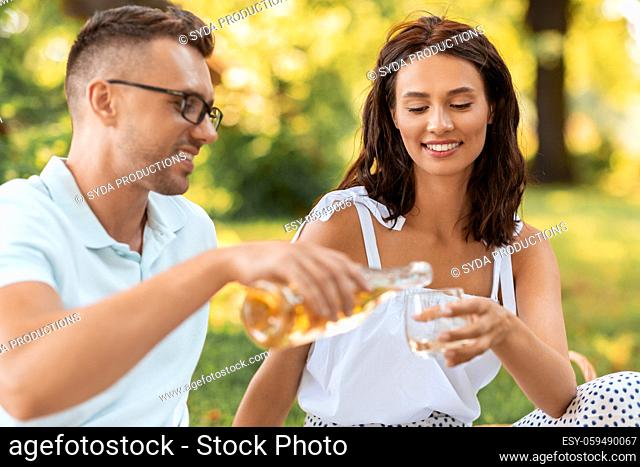 happy couple with wine having picnic at park