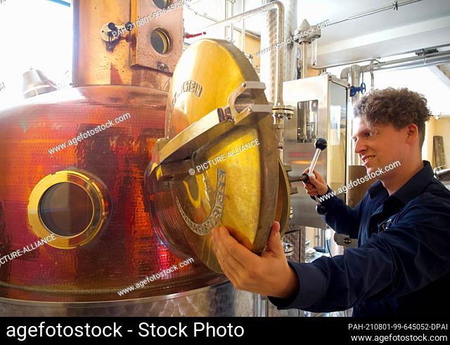 26 July 2021, Brandenburg, Bad Belzig: Tim Eggenstein opens the copper still in the brewhouse of the family business Eggenstein Whisky- und Edelbrandmanufaktur