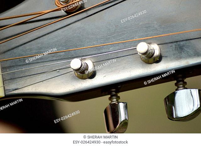 Closeup of the tuning mechanisms of an acoustical, steel-stringed guitar..