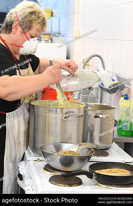 24 March 2020, Saxony, Leipzig: With mouthguards, cook Elke from the ""Alter, Leben und Gesundheit"" association prepares lunch for senior citizens in one of...