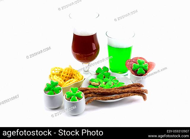 Glass of dark beer glass of green clover plate with appetizers meat chips on white background. St.Patrick 's Day
