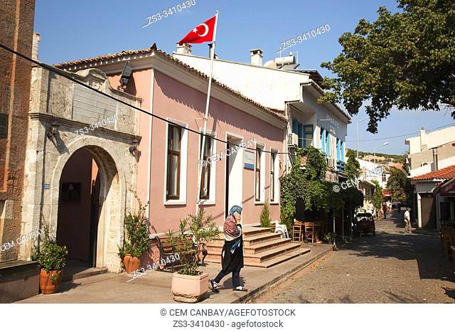 Local woman at the street in front of traditional houses in the town center of the ancient Tenedos, todays Bozcaada island, Bozcaada, Canakkale, Aegean Region
